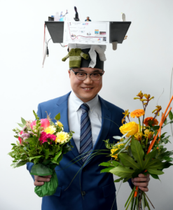 photograph showing Wenchang Wu wearing his doctoral hat and holding flowers in his hands